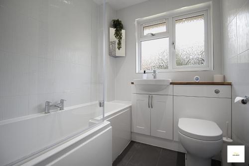 a white bathroom with a toilet and a sink at Camberley Spacious and Comfy 3 Bedroom Home, Next to Frimley Hospital with Parking in Frimley