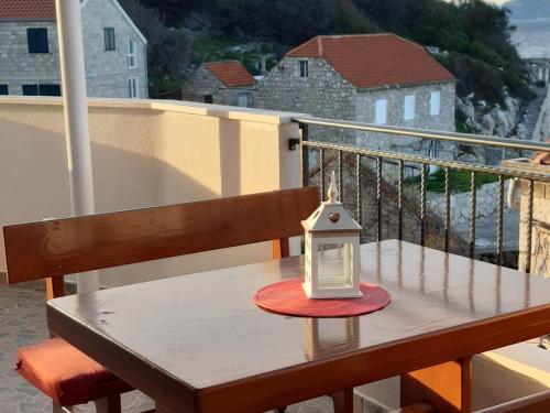 une lanterne assise sur une table en bois sur un balcon dans l'établissement Apartments Cumbelic, à Kozarica