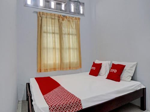 een slaapkamer met een bed met rode kussens en een raam bij OYO 92429 Vania Guest House in Medan