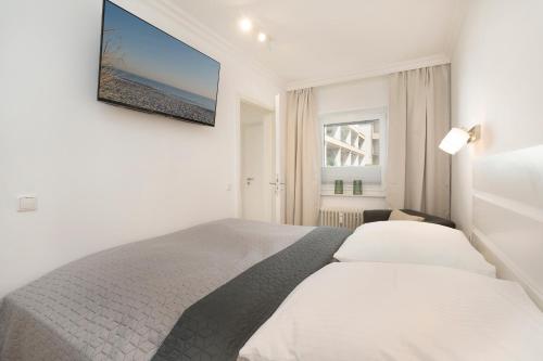 - une chambre blanche avec un lit et une télévision murale dans l'établissement Miramar Wohnung 510, à Grömitz