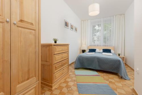 ein Schlafzimmer mit einem Bett, einer Kommode und einem Fenster in der Unterkunft Bałuckiego Apartment Stary Mokotów Warsaw by Renters in Warschau