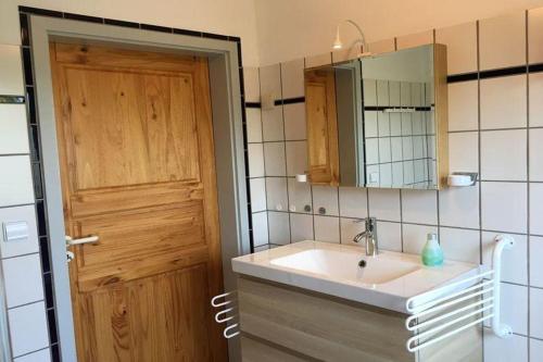 a bathroom with a sink and a wooden door at Haus 52° Nord, Ferienwohnung in Winsen Aller