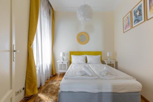 a bedroom with a large white bed with two tables at GDE Károly Apartmant in Budapest