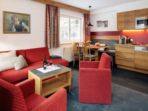 a living room with red furniture and a kitchen at Appartement Désirée inkl der SUPER SOMMER CARD im SOMMER 2025 in Serfaus