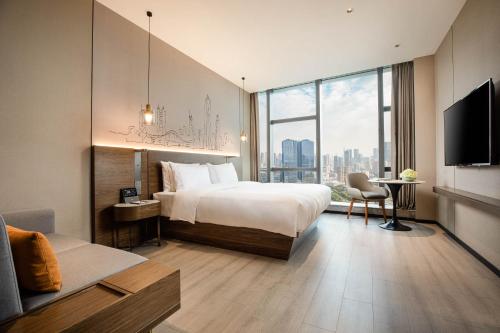 um quarto de hotel com uma cama e uma grande janela em UrCove by HYATT Shenzhen Nanshan Science and Technology Park em Shenzhen