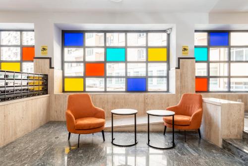 a lobby with two chairs and a table and windows at numa I Verso Apartments in Rome