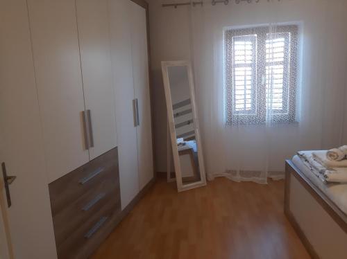 1 dormitorio con espejo, cama y ventana en Holiday Home Nadija, en Brseč