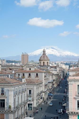 a city street with buildings and snow covered mountains at Ostello degli Elefanti in Catania