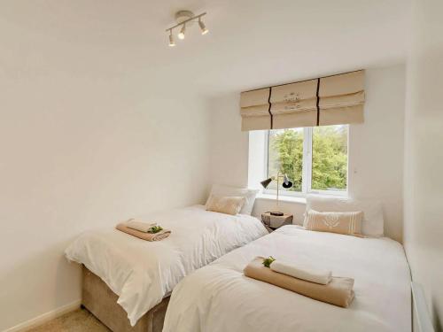 Duas camas num quarto com paredes brancas e uma janela. em Claro Mews Gem em Knaresborough