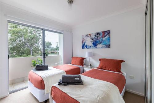 two beds in a room with a window at MikaLex - Walking distance from the beach! in Nelson Bay