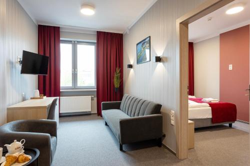 a hotel room with a bed and a couch and a chair at Apartamenty Albatros in Augustów