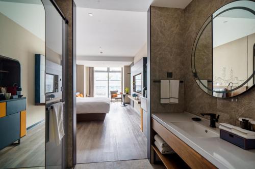 a bathroom with a bed and a sink and a mirror at UrCove by HYATT Futian CBD-毗邻福田站和星河COCO Park 尊享免费迷你吧 in Shenzhen