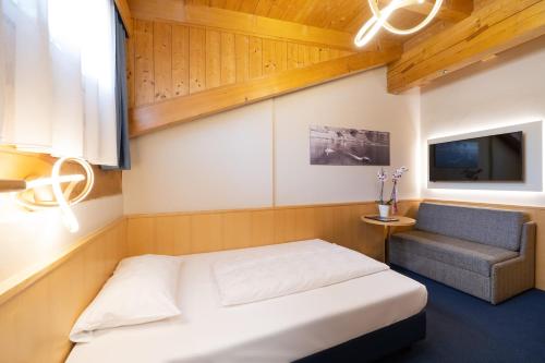 a small bedroom with a bed and a chair at PENSION KLUGHAMMER in Caldaro