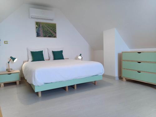 a white bedroom with a bed and a dresser at Gîtes de l'Orée du Bois - Boussières in Boussières