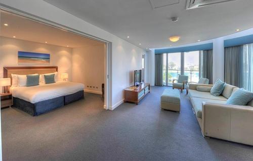 a bedroom with a bed and a living room with a couch at Seashells Mandurah in Mandurah