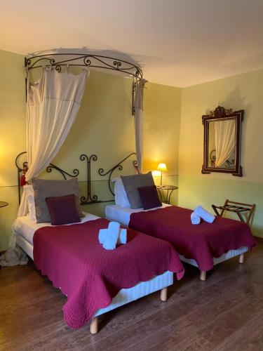 1 dormitorio con 2 camas, mantas moradas y espejo en La Bastide Du Bois Breant en Maubec