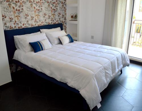 un grande letto con lenzuola e cuscini bianchi in una camera da letto di Kairos Suite a Modugno