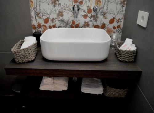 a bathroom with a white sink and baskets on a shelf at Kairos Suite in Modugno