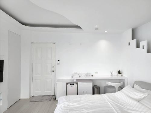 een witte slaapkamer met een bed en een wastafel bij White window sea in Hengchun