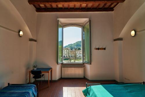 a bedroom with two beds and a large window at Ostello Antica Filanda in Santa Sofia