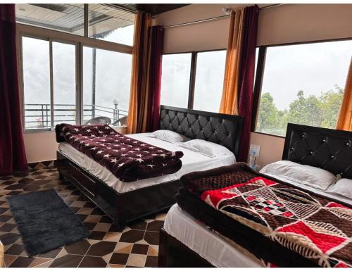twee bedden in een kamer met ramen bij Anjali Homestay, Ukhimath in Ukhimath