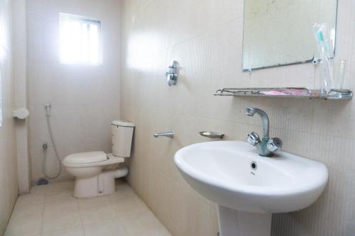 a white bathroom with a sink and a toilet at Hotel Golden Inn Chattagram Ltd in Chittagong