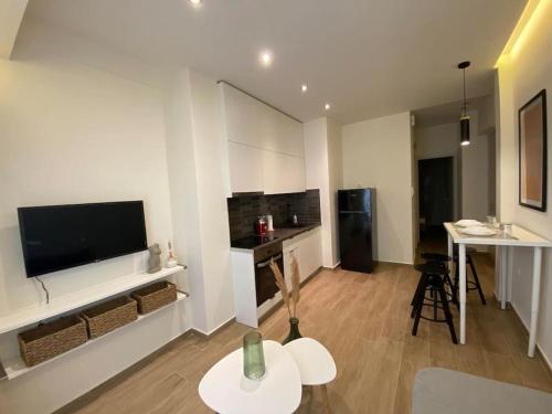 a living room with a tv and a table and a kitchen at Piraeus cozy appartment rental in Piraeus