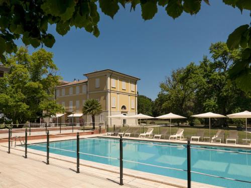 a pool with chairs and umbrellas in front of a building at Villa Abbondanzi Resort in Faenza