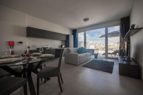 a kitchen and living room with a table and a couch at The Address Seafront Suites with Hot Tub in Pieta