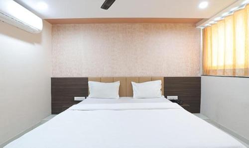 Un dormitorio con una gran cama blanca y una ventana en FabHotel The Heaven en Ahmedabad