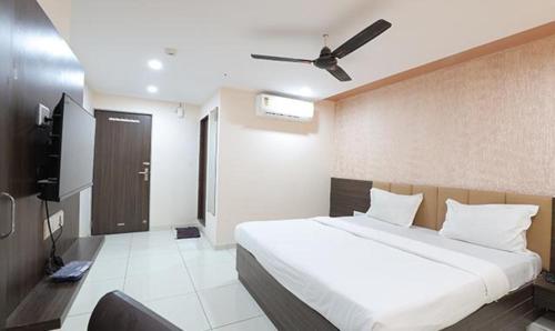 1 dormitorio con 1 cama grande y ventilador de techo en FabHotel The Heaven en Ahmedabad
