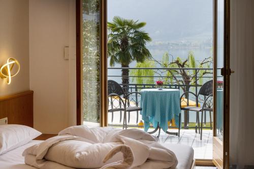 a bedroom with a bed and a balcony with a table at PENSION KLUGHAMMER in Caldaro