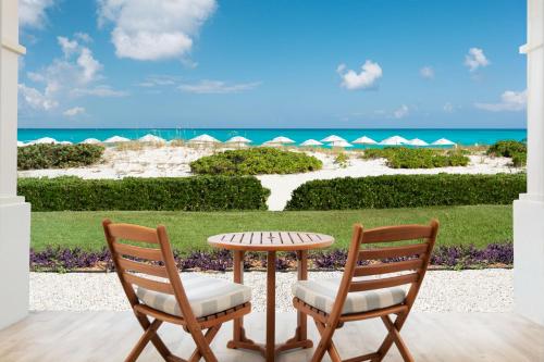 a patio with a table and two chairs and the beach at Alexandra Resort - All-Inclusive in Grace Bay