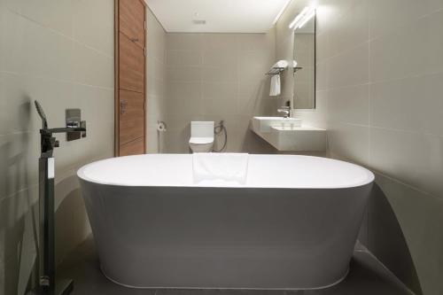 a white bath tub in a bathroom with a sink at Flamingo Resort Cat Ba in Cat Ba