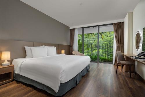 a hotel room with a large bed and a desk at Flamingo Resort Cat Ba in Cat Ba