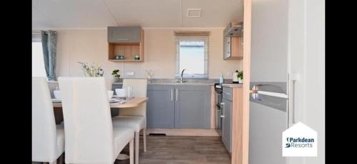 Charming 3-Bed Caravan in Colchester Mersea island في كولشستر: مطبخ صغير مع طاولة وأدوات مطبخ