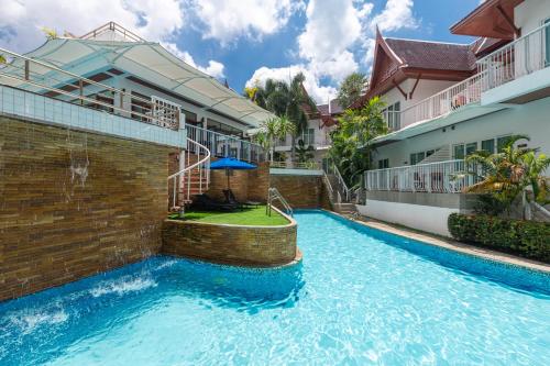 a swimming pool in front of a building at Phunawa Resort Phuket Karon Beach - SHA Plus in Karon Beach
