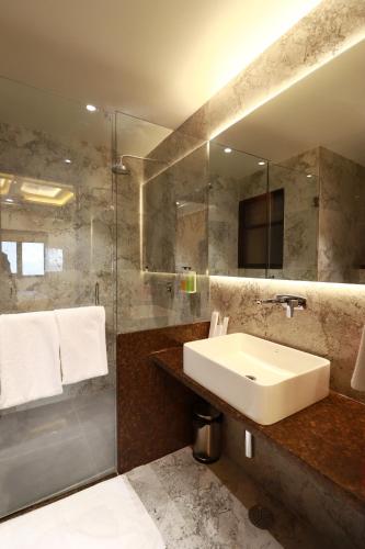 a bathroom with a sink and a glass shower at Four Petals Executive by LHMS in Akalkot