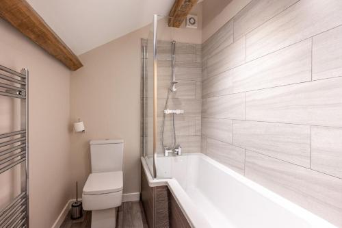 a bathroom with a tub and a toilet at Meadow Barn in Rishworth