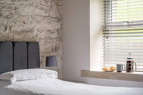 a bedroom with a white bed and a window at Meadow Barn in Rishworth