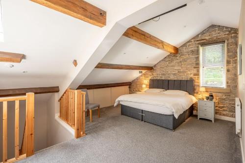 a bedroom with a bed and a stone wall at Meadow Barn in Rishworth