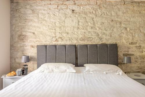 a bedroom with a large white bed with a brick wall at Meadow Barn in Rishworth