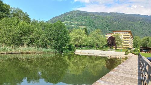 a wooden bridge over a lake with a building in the background at KARL Haus KMB Seeappartement am Ossiacher See mit direktem Seezugang, Hallenbad in Bodensdorf
