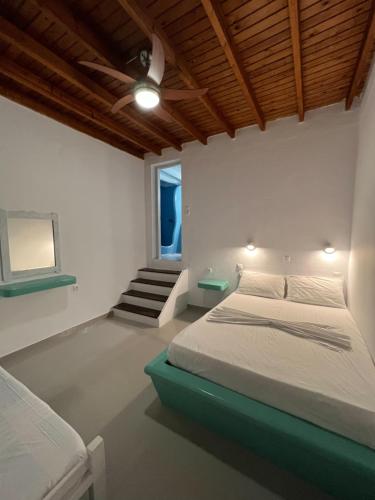 a white bedroom with a bed and a staircase at Martin Rooms in Iraklia