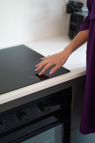 a woman in a kitchen with her hand on a stove at The Address Seafront Suites with Hot Tub in Pieta