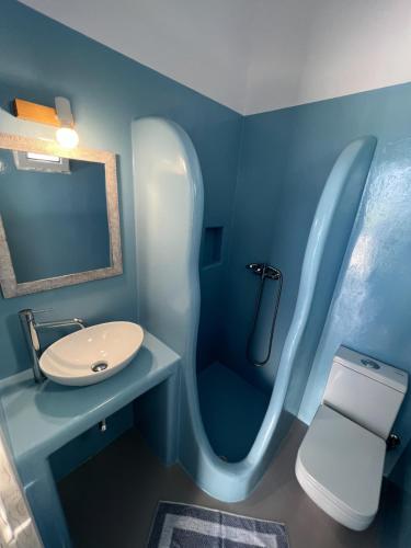 Baño azul con lavabo y aseo en Martin Rooms, en Iraklia
