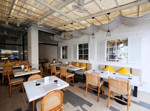 a restaurant with white tables and chairs and yellow cushions at La Vista Patong Hotel in Patong Beach