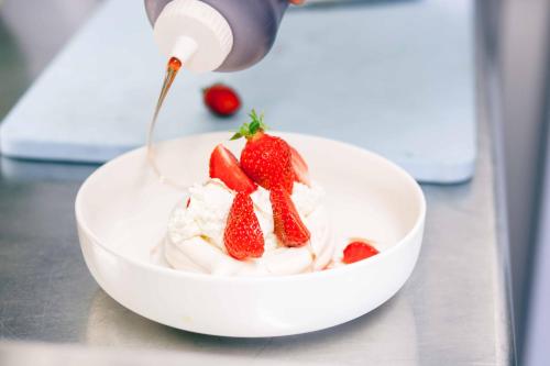 a bowl of whipped cream with strawberries on a counter at Logis Hôtel La Bastide De Grignan & Restaurant "La Chênaie" in Grignan