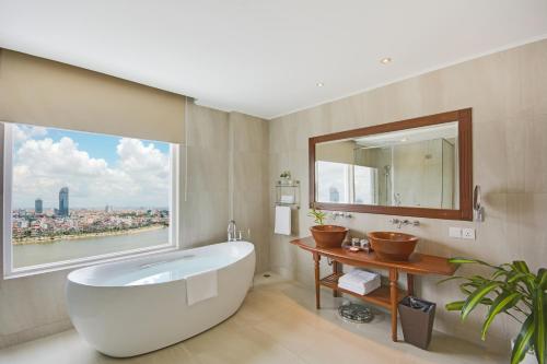 un bagno con una grande vasca e una grande finestra di Sokha Phnom Penh Hotel a Phnom Penh