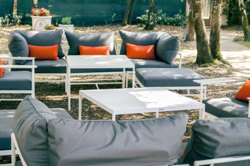 a group of couches and tables with orange pillows at Logis Hôtel La Bastide De Grignan & Restaurant "La Chênaie" in Grignan